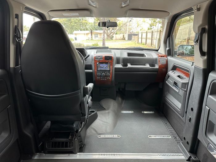 The interior of the MV-1 handicap accessible vehicle, with a view looking toward the front, from the back seat, showing a driver's seat, and an empty space for a wheelchair in the passenger seat area.
